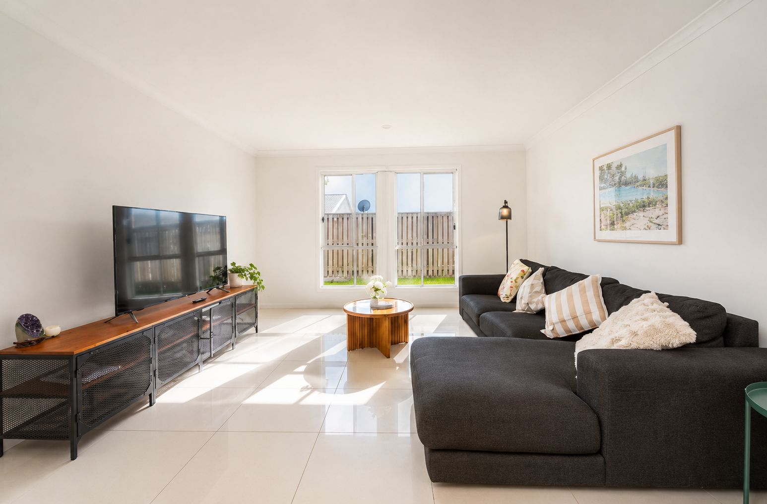 A modern living room with a flat-screen TV, a dark grey sofa, and a wooden coffee table.