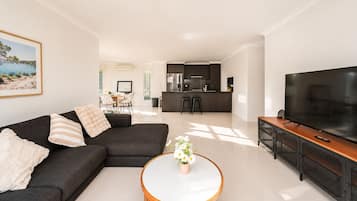 A modern living room with a sofa, a coffee table, and a TV.