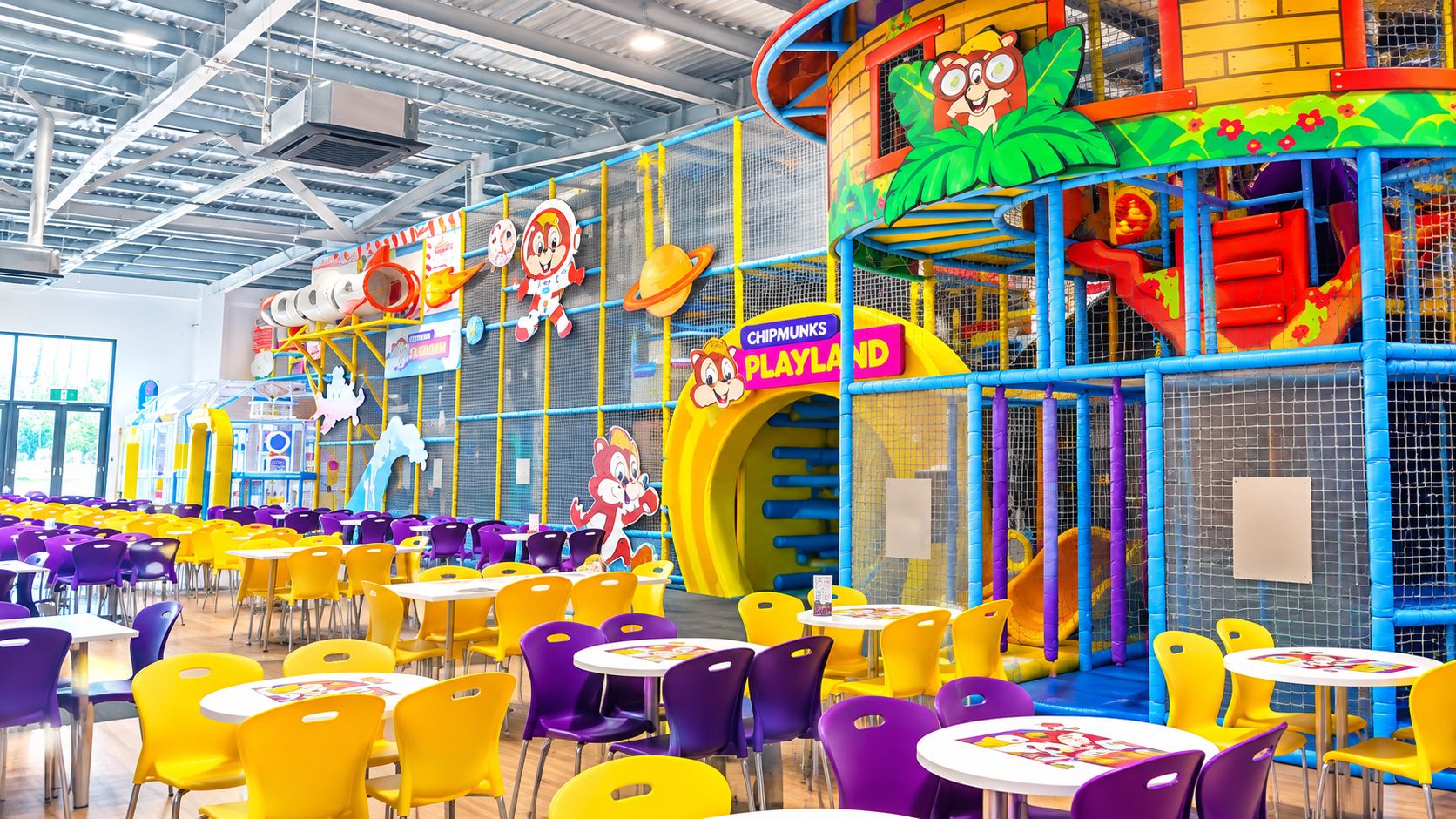 A children's play area with colorful play structures and tables with chairs.