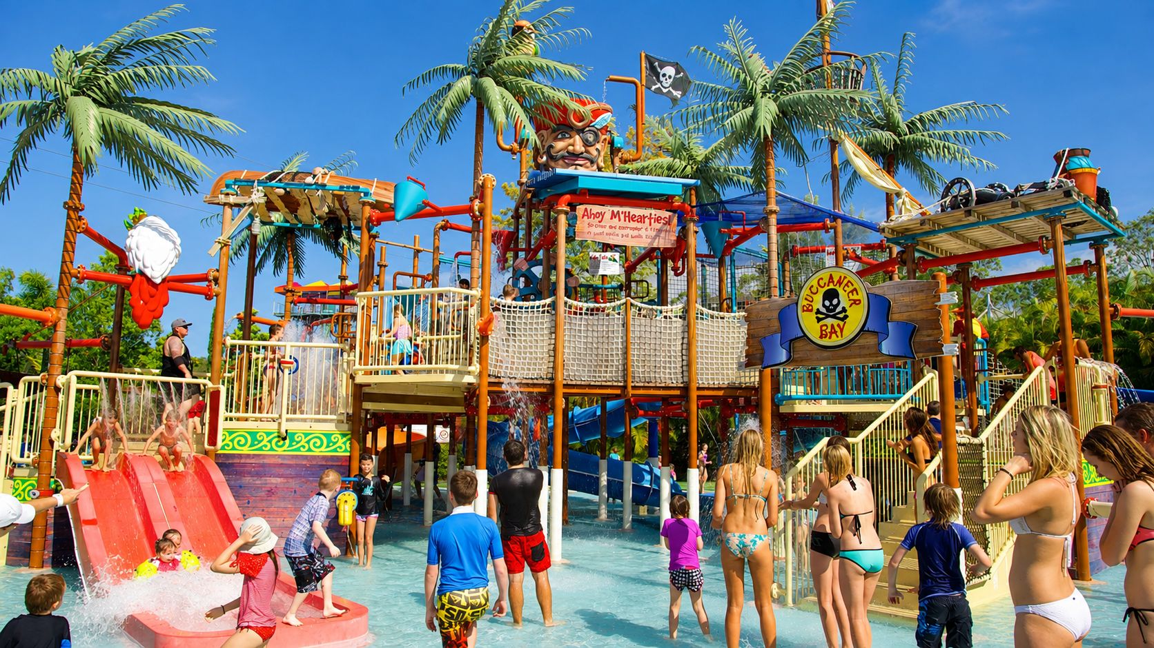 A water park with slides, a pirate-themed play area, and palm trees.