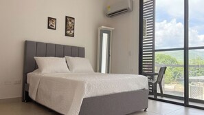 A bedroom with a bed, a window with blinds, and a door. - Your Getaway in Pozos Colorados | Beach and Pools. 10 minutes from the airport. (Santa Marta)