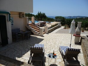 Eine Terrasse mit Steinböden, Gartenmöbeln, einem Pool und Meerblick.