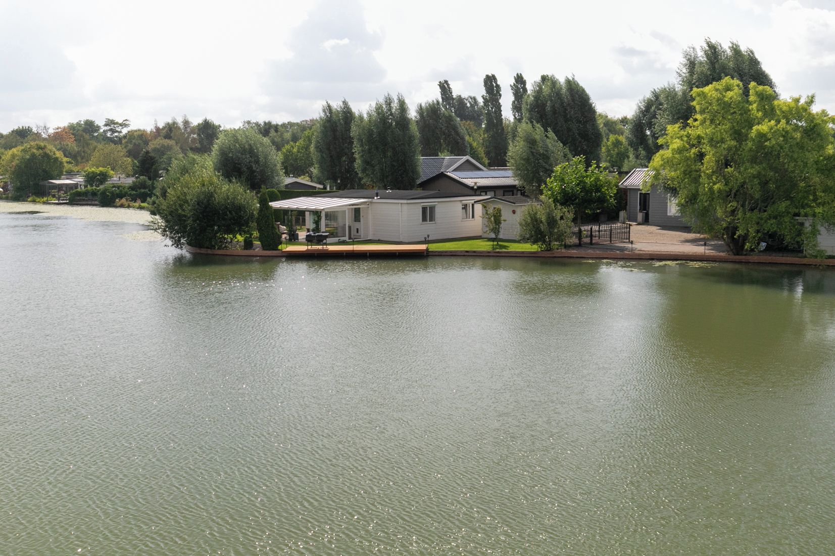 Une propriété au bord du lac comprenant une maison, un quai et un petit bateau.