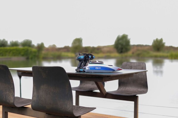 A table with a police speedboat model and chairs by a calm lake.
