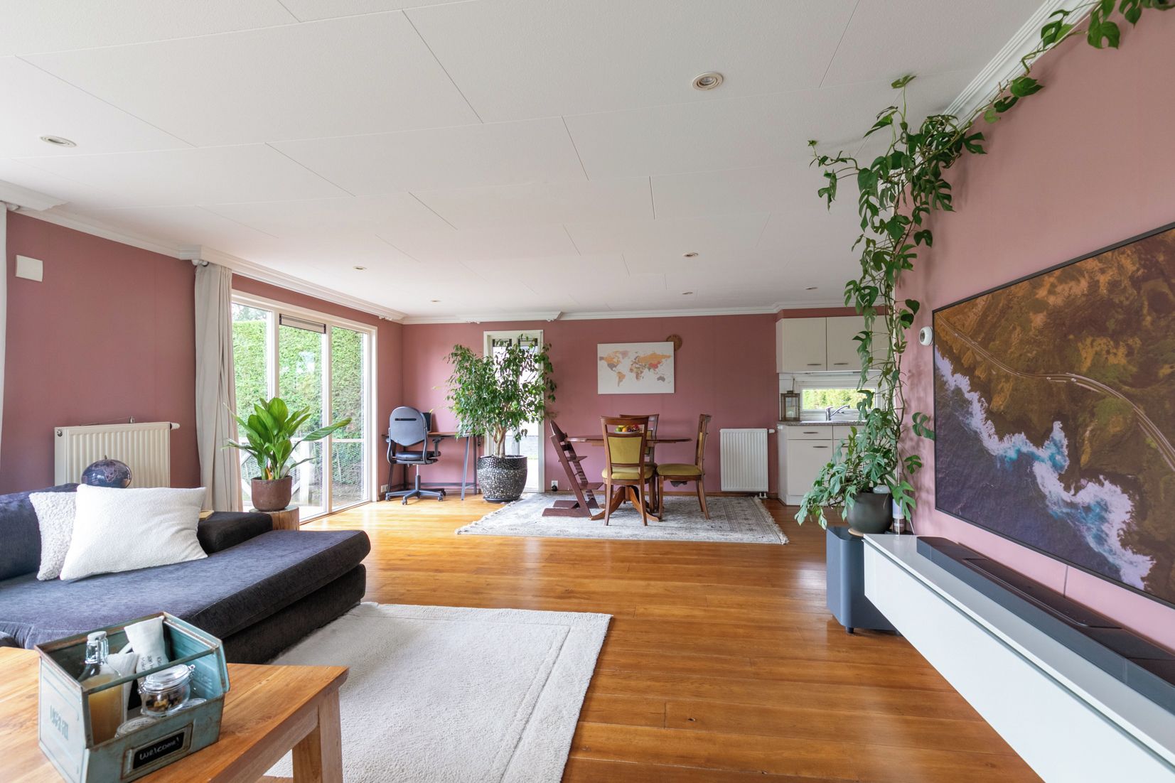 A living room with a sofa, dining table, chairs, and a large window.