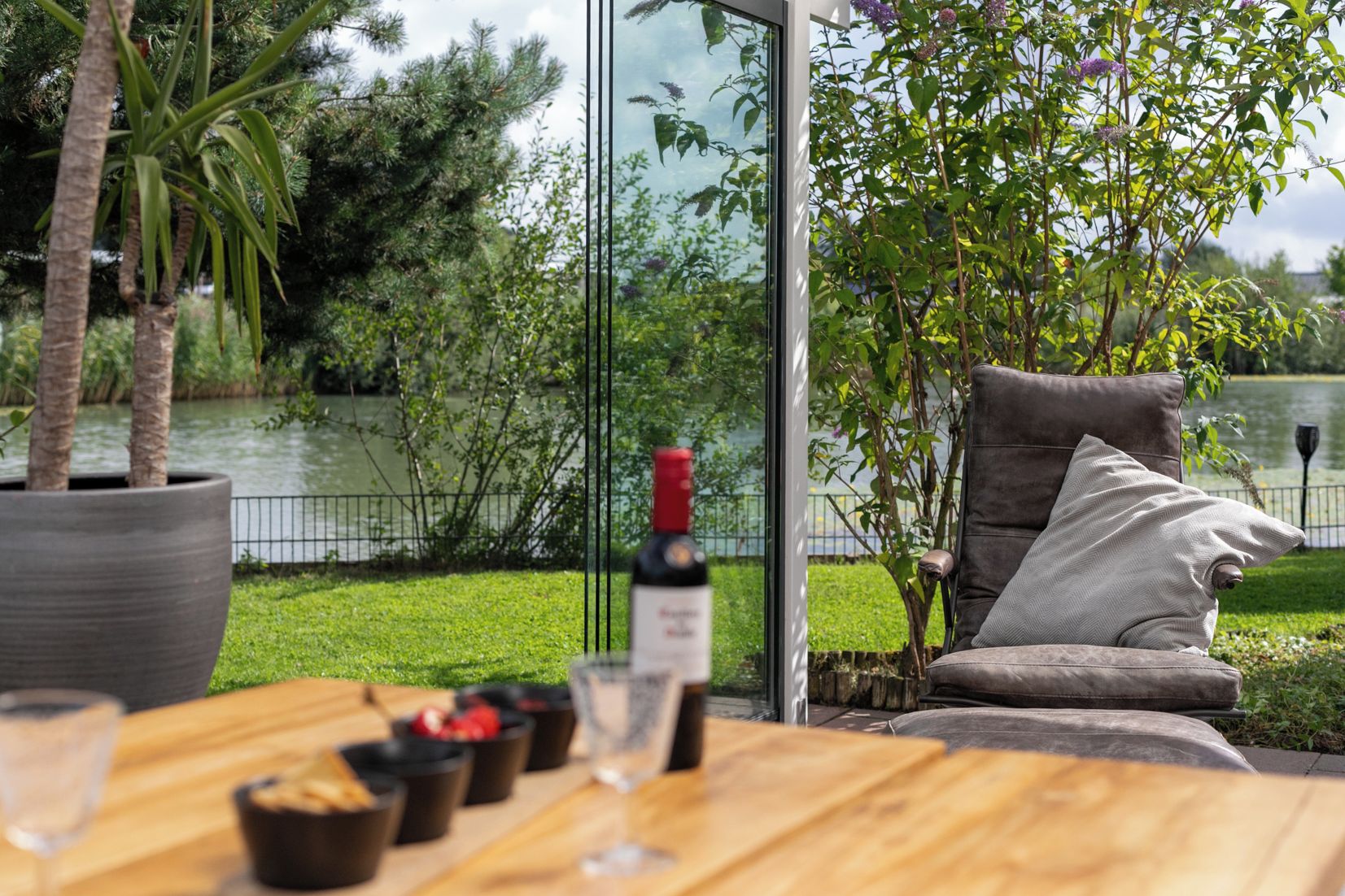 An outdoor seating area with a table, chairs, and a bottle of wine.