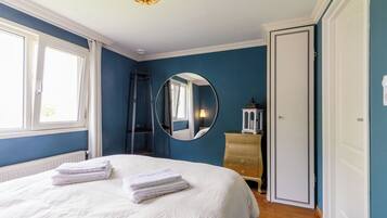 A bedroom with a bed, a dresser, a mirror, and a window.