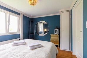 A bedroom with a bed, a dresser, a mirror, and a window.