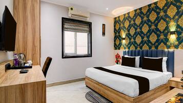A hotel room with a bed, bedside tables, a desk, and a window.