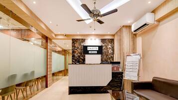A reception area with a ceiling fan, a reception desk, a bulletin board, and a seating area.