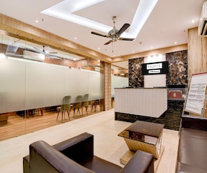 Een modern interieur met een receptiebalie met de naam 'PALETTE', een plafondventilator en een zithoek met tafels en stoelen.
