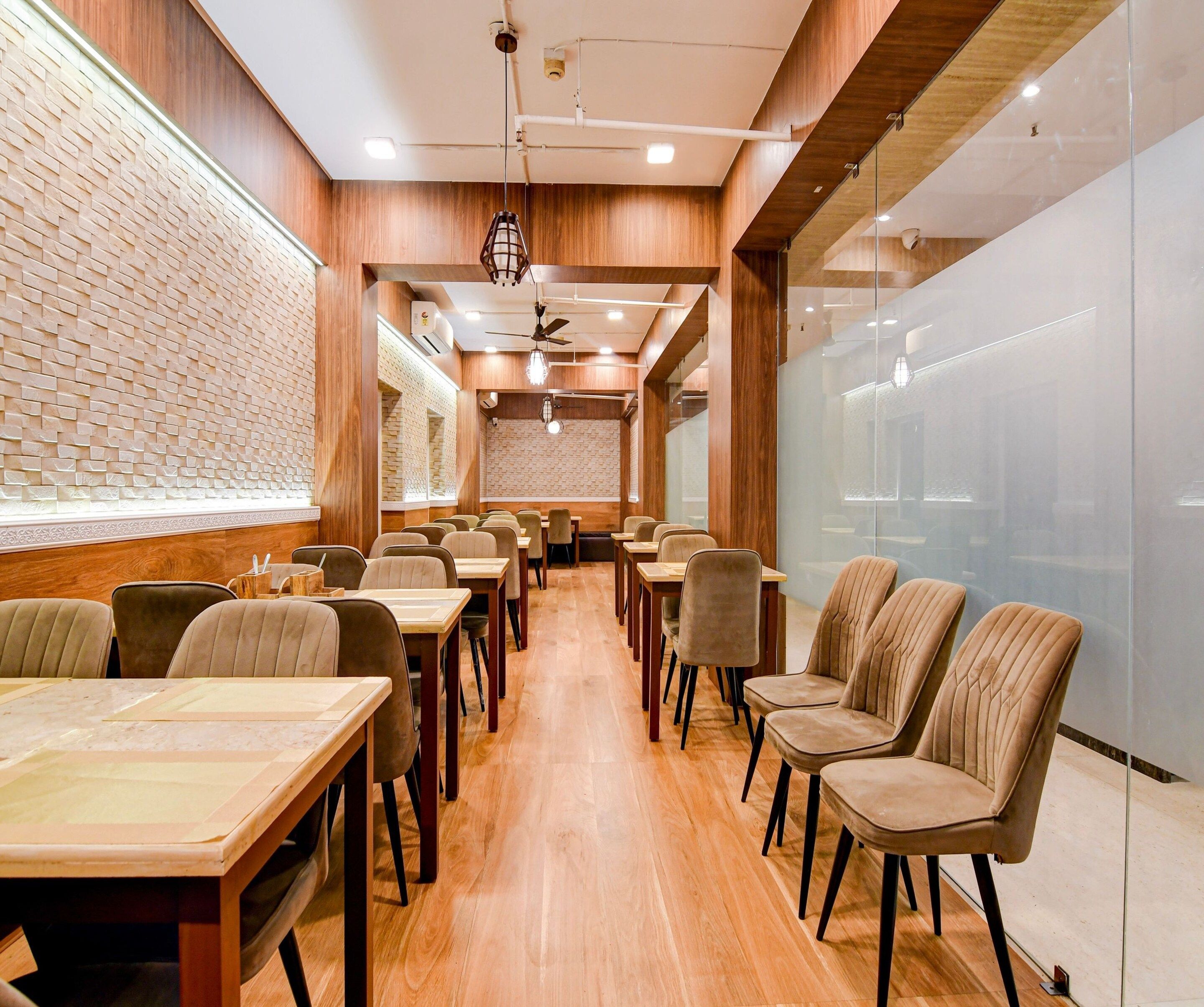 A restaurant interior with wooden walls, brick accents, and a long counter with chairs.