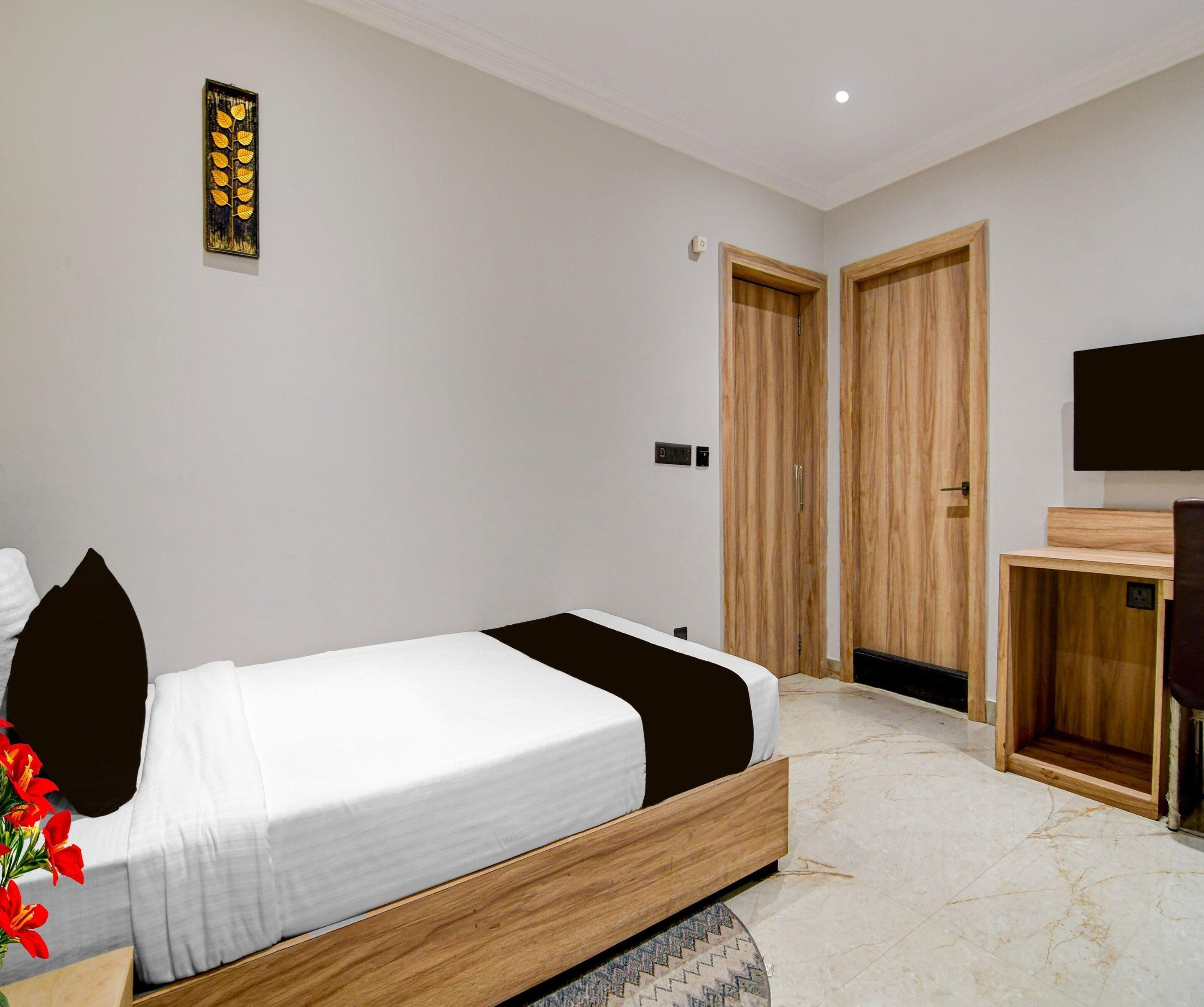 A modern bedroom with a bed, wooden wardrobe, and a television.