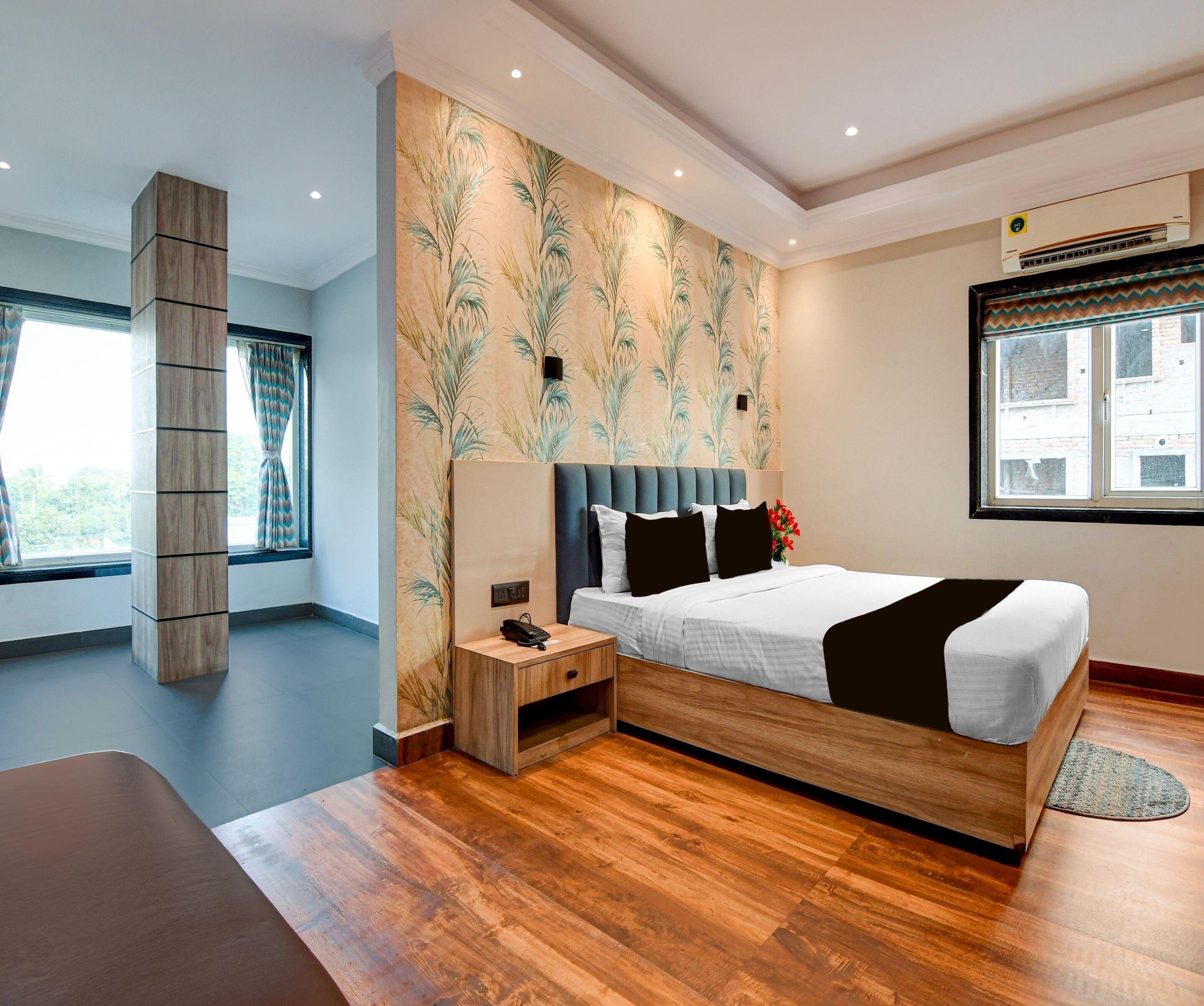 Una habitación de hotel moderna con piso de madera, una cama con cabecera, una mesita de noche, aire acondicionado instalado en la pared y una ventana con vistas.