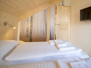 A bedroom with a bed, a bedside lamp, a door, and a wall-mounted television. - Cabin With 1 Bedroom (Sankt Georgen am Kreischberg)