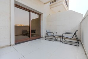 A balcony with a sliding glass door, two chairs, and a small table. - HAVN - 1 Bedroom Apartment in G24 Tower, JVC (Dubai)