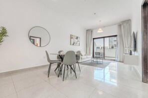 Un salon moderne comprenant un coin repas, un canapé, une table basse et une grande fenêtre avec des rideaux.