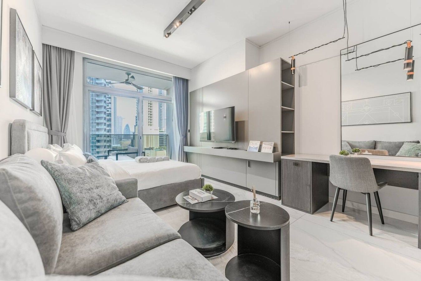 A modern hotel room with a large bed, a desk, and a view of the city.