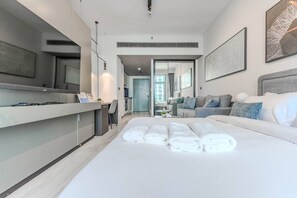 Ein modernes Hotelzimmer mit einem großen Bett, einer Sitzecke mit einer Couch, einem Esstisch und einer Küchenzeile.