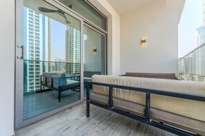 En balkon med sofa og bord, en glasdør der fører ud, og udsigt over bybilledet.