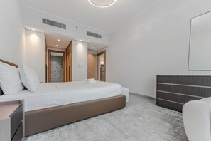 Ein modernes Hotelzimmer mit einem großen Bett, einem Nachttisch, einer integrierten Bank und einem Kleiderschrank.