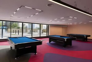A pool table area with three tables, large windows, and a modern ceiling design. - HAVN - NEW 1 Bedroom in Neva Residences, JVC (Dubai)