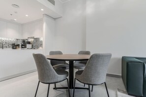 A modern dining area with a round table and four grey upholstered chairs. - HAVN - NEW 1 Bedroom in Neva Residences, JVC (Dubai)