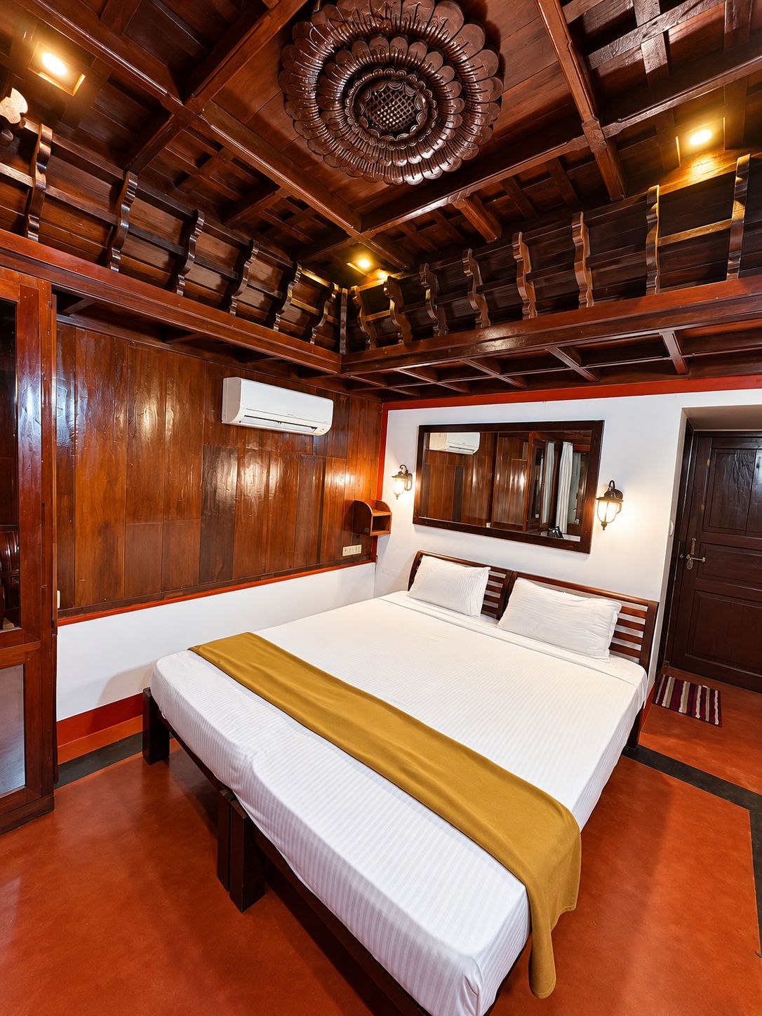 Een hotelkamer met een groot bed, houten plafond en ingebouwde airconditioning.