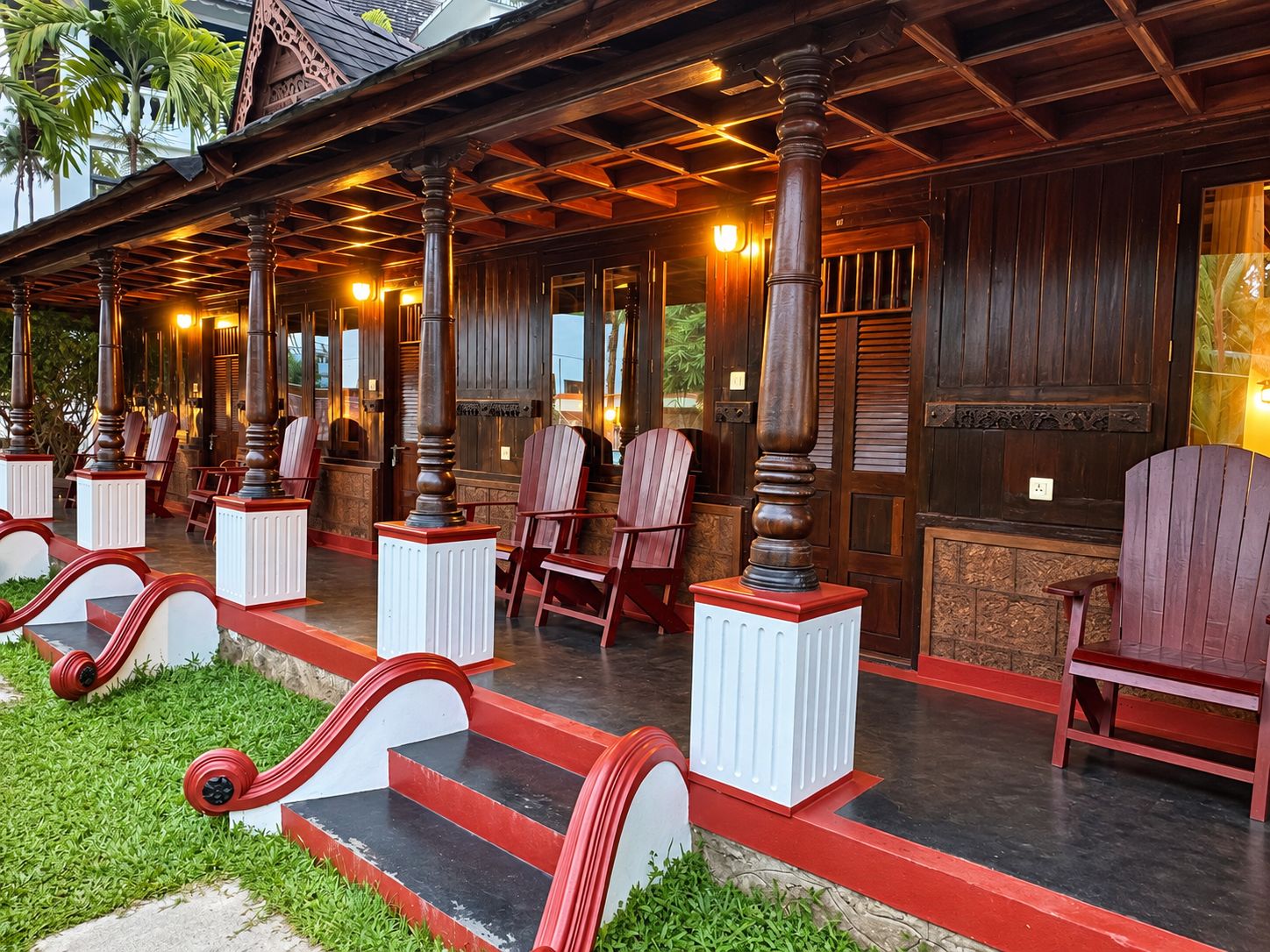 A wooden building with a porch, red and white chairs, and a staircase.