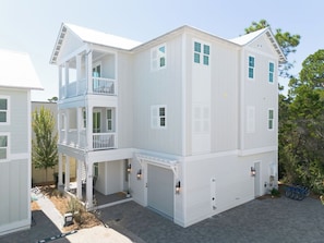 A two-story building with a balcony, a garage, and a driveway. - Luxury Home, Gourmet Kitchen, Sleeps 14, Balconies,Community Pool, Grayton Beach (Santa Rosa Beach)