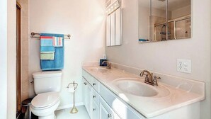 Un baño con inodoro, dos lavamanos, un espejo y un toallero.