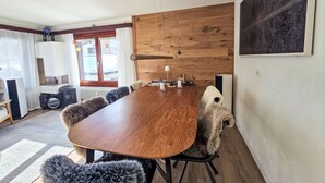 A dining area with a wooden table, chairs, and a view of the outside. - Wohnung Auri by Interhome (Saas-Fee)