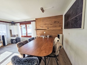 Een eetgedeelte met een houten tafel, stoelen en uitzicht op het omliggende landschap.