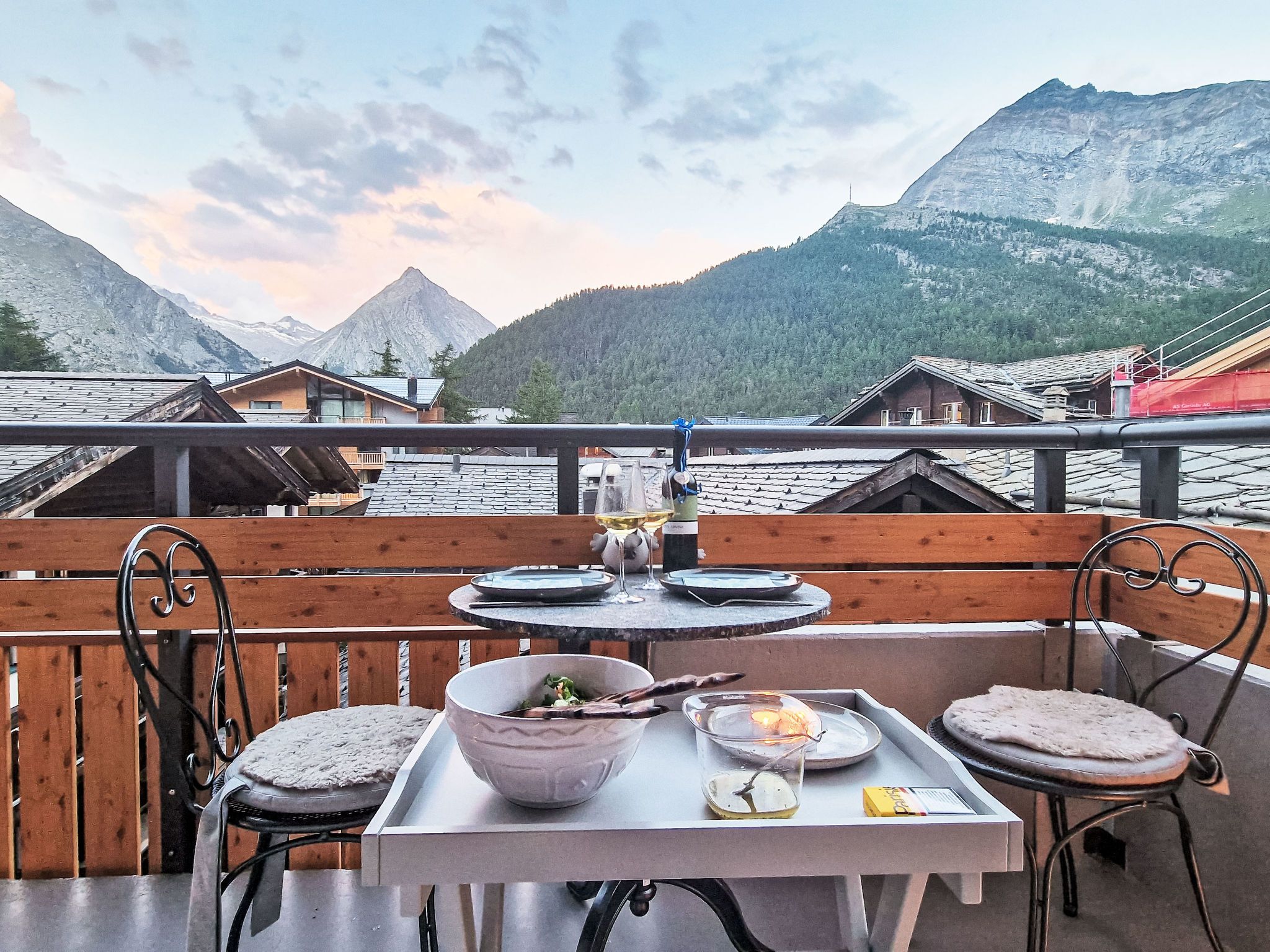 Une terrasse avec une table dressée pour le dîner, offrant une vue sur un paysage montagneux.