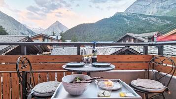 Une terrasse avec une table dressée pour le dîner, offrant une vue sur un paysage montagneux.