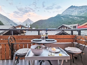 Une terrasse avec une table dressée pour le dîner, offrant une vue sur un paysage montagneux.