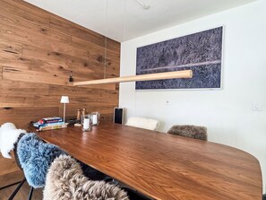 Une salle de conférence avec une table en bois, des chaises, un tapis blanc et moelleux, une lampe et un tableau accroché au mur.