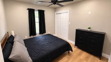 Un dormitorio con cama, cómoda, ventilador de techo y puerta.