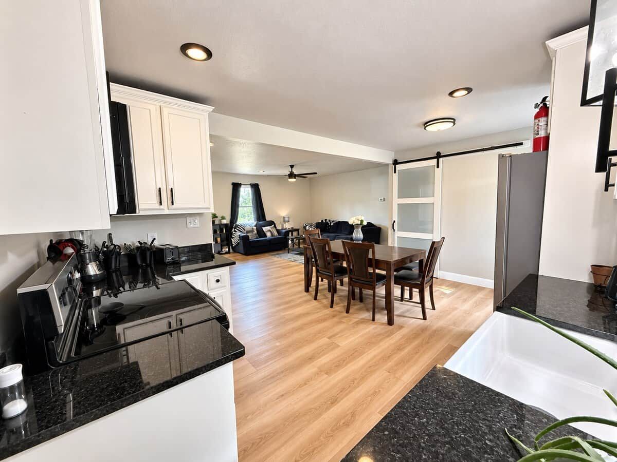 A modern kitchen with a dining area, wooden flooring, and a visible fire extinguisher.