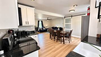 A modern kitchen with a dining area, wooden flooring, and a visible fire extinguisher.