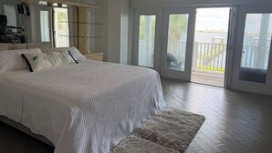 Quarto com uma cama grande, um espelho e vista para uma varanda.