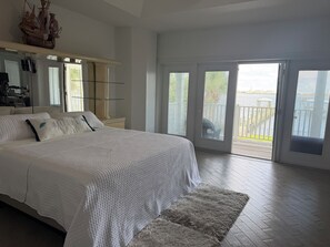 Ein Schlafzimmer mit einem großen Bett, einem Spiegel und Blick auf einen Balkon.