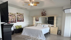 Quarto com cama, penteadeira, espelho e ventoinha no teto.