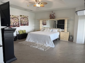 Ein Schlafzimmer mit Bett, Schminktisch, Kommode, Spiegel und Deckenventilator.