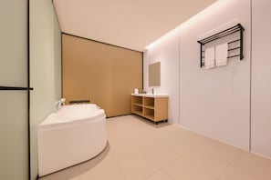 Een moderne badkamer met een vrijstaand bad, een wastafel met spiegel en een handdoekrek.