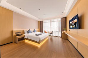 Una habitación de hotel moderna con una cama grande, mesitas de noche, un escritorio y un televisor.