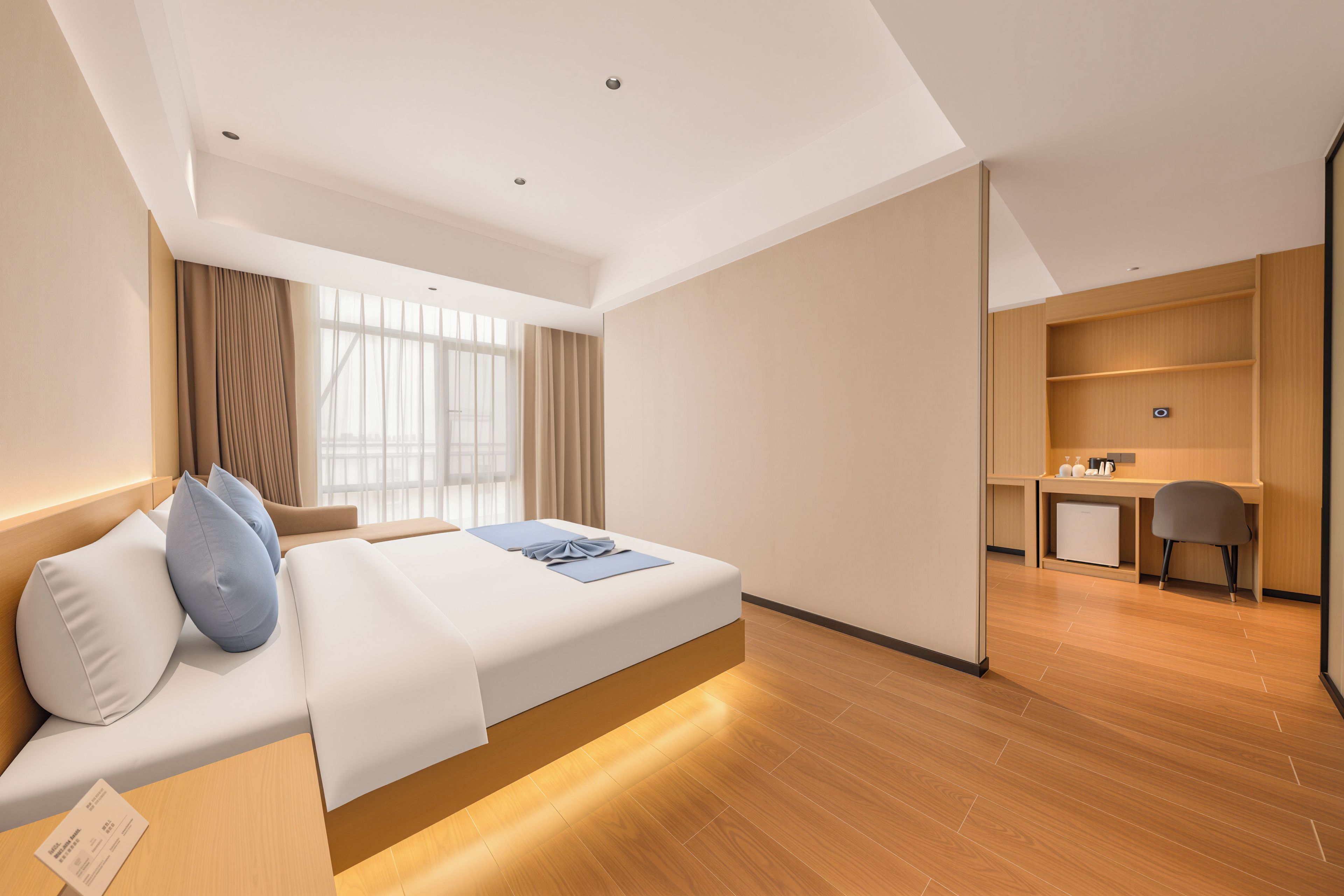 A modern hotel room with a bed, a desk, and a kitchenette.