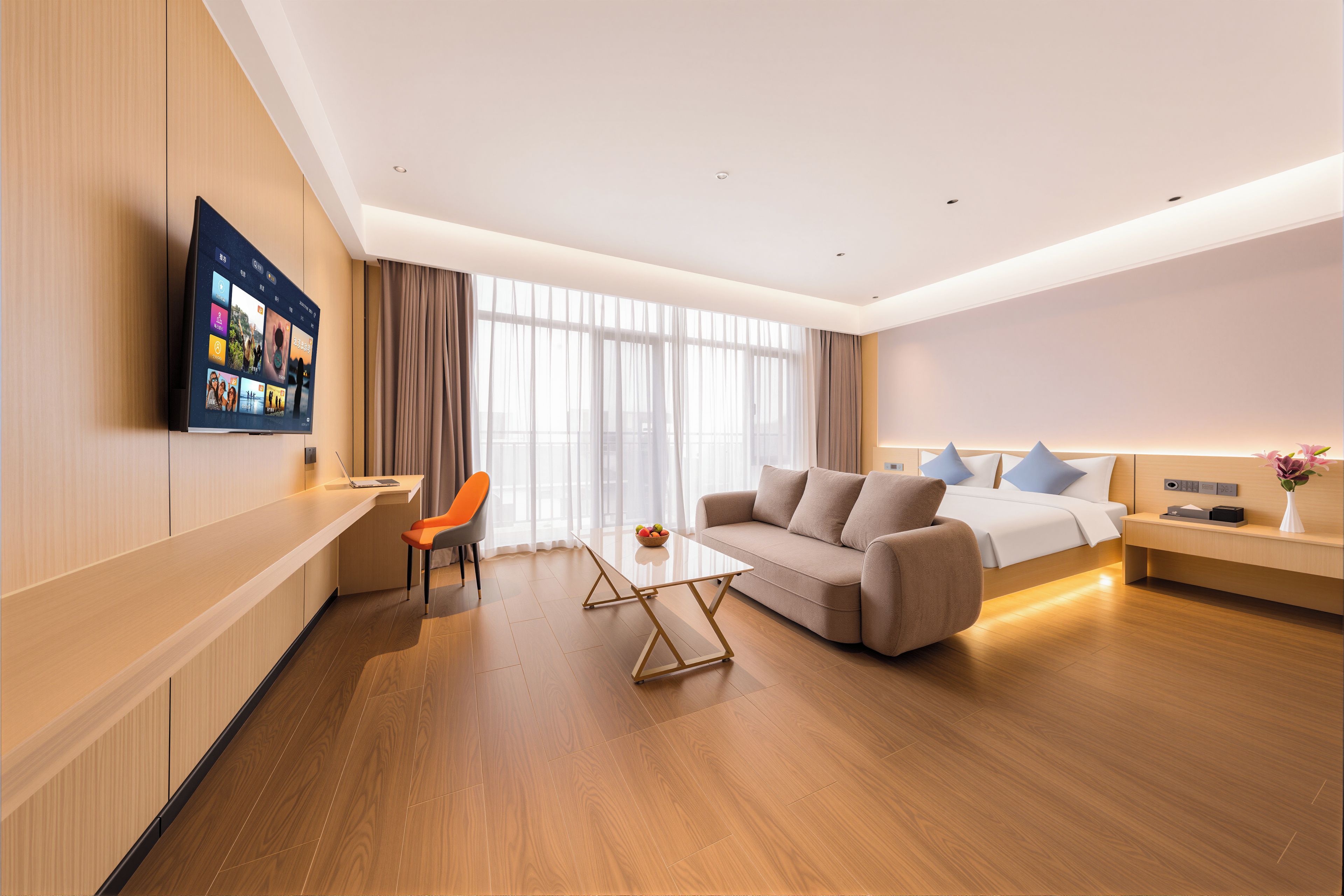 Een moderne hotelkamer met een flatscreen televisie, een bank, een eettafel en een bed.