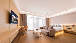 A modern hotel room with a flat-screen TV, a sofa, a dining table, and a bed. - Liaoning International Hotel (LaosVientiane)