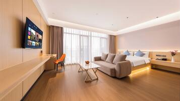 Een moderne hotelkamer met een flatscreen televisie, een bank, een eettafel en een bed.
